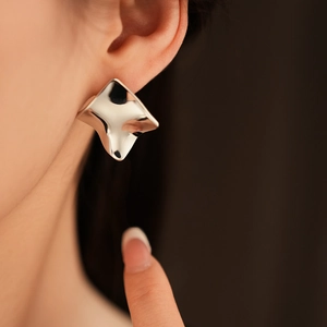 Gros plan de boucles d'oreilles carrées torsadées argentées portées par un mannequin