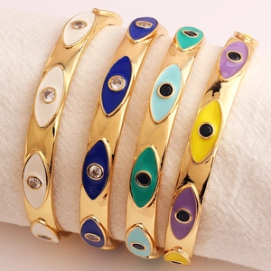 Golden evil eye open bracelets with colorful enamel and zircon stones on white fabric