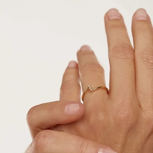 Close-up of a V-shaped gold ring with three sparkling zircons on a model finger
