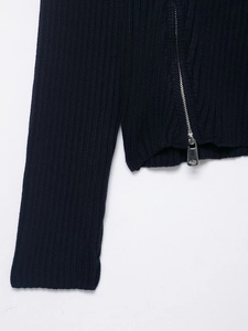 Detail of ribbed knit texture and silver metal zipper on navy blue zip-up cardigan