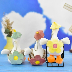 Vue arrière de trois mignons pendentifs oie en peluche avec fleurs colorées et chaînes dorées