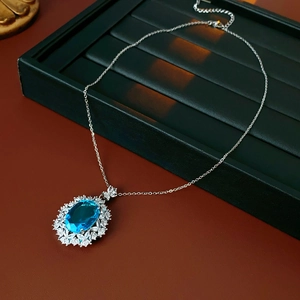 Detailed macro view of an oval blue gemstone flower necklace on green velvet tray