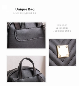 Detail of black pebbled leather backpack showing sturdy handles and gold metal hardware