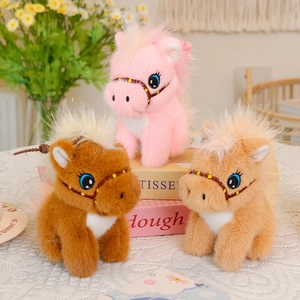 Detailed view of three plush pony charms in pink and brown with glittery manes and blue eyes