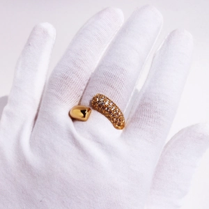 Close-up of a gold-plated open ring featuring sparkling pavé zircon stones on white gloves