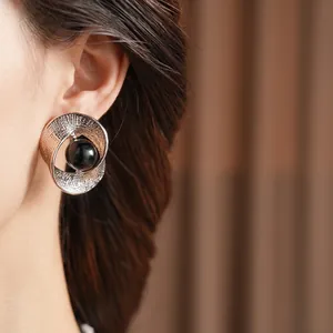 Artistic silver twisted earrings with hammered texture and black center bead on model