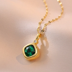 Elegant gold square green gemstone necklace with white diamond accent on pink silk background
