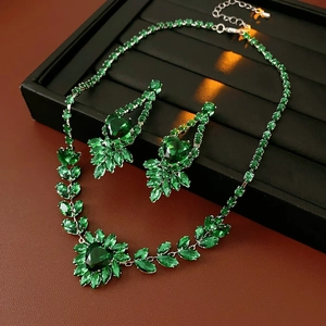 Detailed view of green emerald-style necklace and earring set on black jewelry tray
