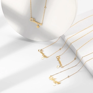 Detail of gold zodiac necklaces with cursive script pendants and zircon accents