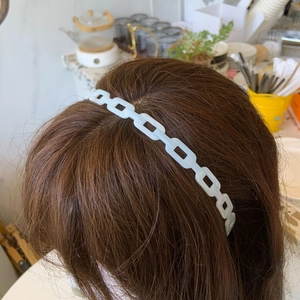 Detail of light blue acetate chain headband worn on model with jelly-like translucent finish