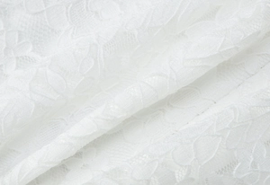 Dettaglio del tessuto in pizzo bianco con delicato ricamo floreale e trama in rete