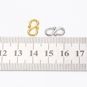 Stainless steel S-shape jewelry clasps in gold and silver finish with metric ruler for scale