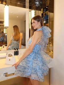 Detail of blue floral halter dress featuring backless design with large bow and ruffled hem