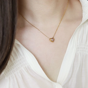 Close-up of a titanium heart necklace with pink gemstone pendant on model's neck