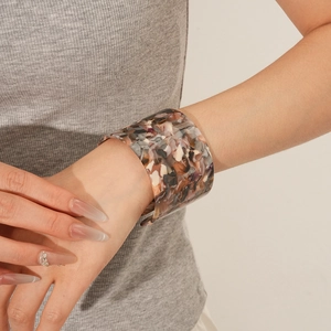 Macro shot of wide open cuff bracelet with colorful acetate tortoiseshell pattern on wrist