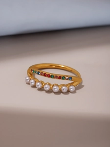 Détail macro d'une bague dorée 18 carats avec double rangée de perles et zircons colorés