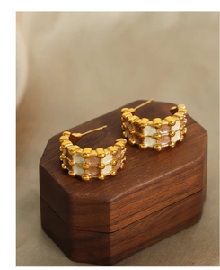 Close-up of checkered enamel hoop earrings on a vintage wooden jewelry box