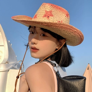 Detail of hand-woven straw cowboy hat with pink stars against a clear blue sky