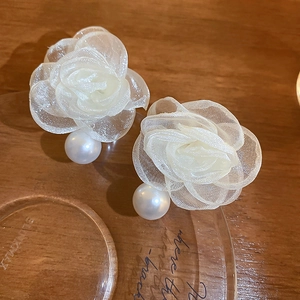 Macro view of lace flower earrings with soft white organza petals and a hanging pearl drop