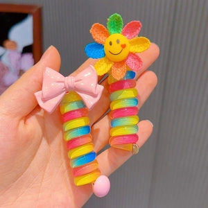 Detailed view of colorful spiral hair ties with cute pink bow and smiling flower charms