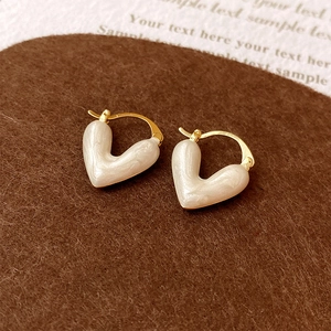 Macro d'une boucle d'oreille cœur plaquée or avec émail nacré blanc raffiné
