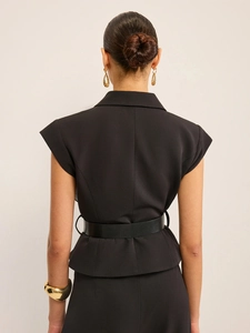 Détail du gilet blazer noir sans manches avec ceinture fine en cuir et bijoux dorés