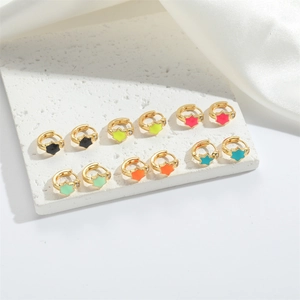 Set of six pairs of gold star earrings with colorful enamel charms on white stone