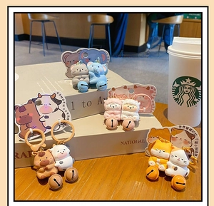 Close-up of cute magnetic animal couple keychains with colorful bells on display