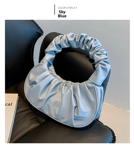 Detailed view of sky blue pleated PU leather crescent handbag on black chair