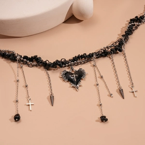 Detail of gothic necklace featuring black stone beads with spiked heart and cross charms