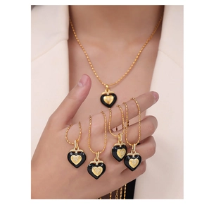 Detail of vintage gold-plated heart pendant necklace with black enamel and zircons