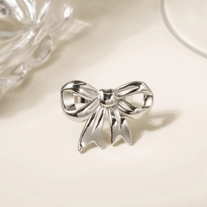 Elegant 18K gold-plated stainless steel bow ring with polished silver finish on warm background