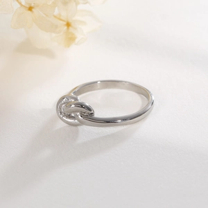 Detailed close-up of a silver knot ring featuring a clean minimalist polished metal finish