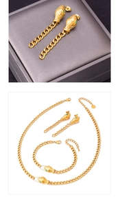 Detailed view of golden snake-themed jewelry set with green gemstone accents and tassels