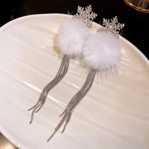 Detail of snowflake earrings featuring white fur pom-poms and silver tassel chains