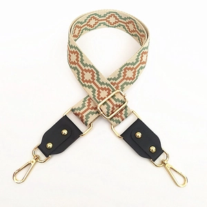 Close-up of adjustable ethnic jacquard bag strap with geometric patterns and gold buckles