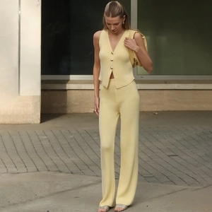 Dettaglio della trama a maglia su gilet giallo tenue e pantaloni coordinati a gamba larga