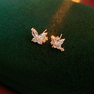 Vue macro de boucles d'oreilles papillon dorées avec pierres sur velours vert