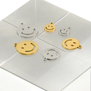 Macro detail of smiley face pendants in gold and silver steel on acrylic base