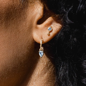 Close-up of S925 silver C-shaped drop earrings with light blue gems on the ear