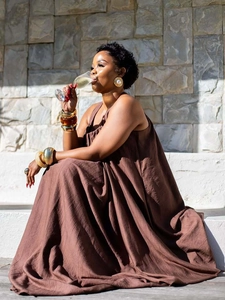 Detail of dark brown sleeveless dress with pleated fabric and elegant pearl gold jewelry
