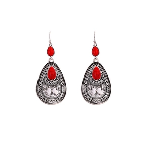 Close-up of vintage silver boho earrings with red teardrop stones and carved details