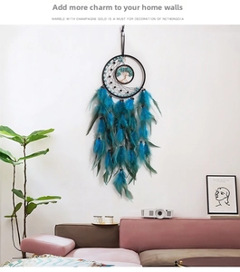 Detail of bohemian life tree dream catcher with blue feathers on a white wall decor