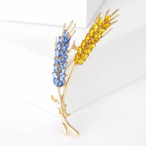 Detailed view of wheat brooch with blue and yellow crystals on golden base