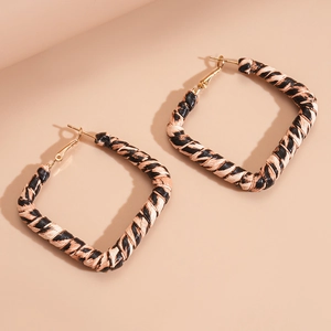 Detailed view of square geometric hoop earrings with beige and black woven fabric texture
