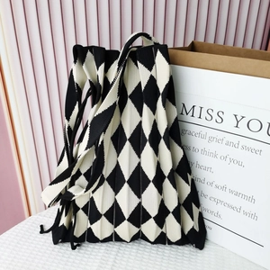 Detailed close-up of a black and white diamond knit pattern shoulder bag on textured surface