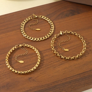 Close-up of three gold stainless steel bracelets including Cuban and box chain styles