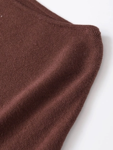 Detailed close-up of dark brown knit fabric showing ribbed edge and fine texture