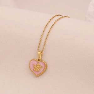 Close-up of pink heart pendant with golden angel relief on a gold chain necklace