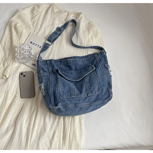 Vue à plat d'un sac à bandoulière en denim bleu vintage avec sangle réglable sur tissu